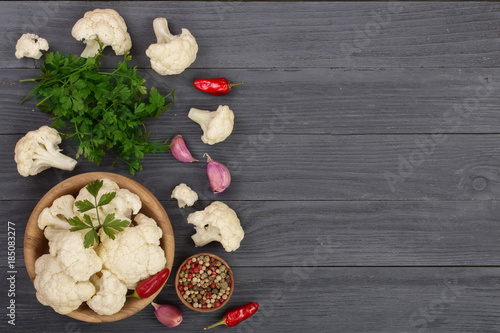 Fresh cauliflower with garlic and chili peppers on black wooden background with copy space for your text. Top view