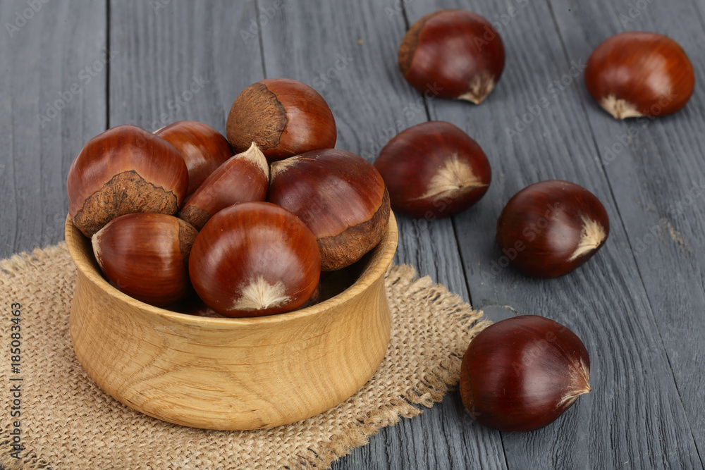 chestnut in wooden bowl on black wooden background chestnut in wooden bowl on black wooden background