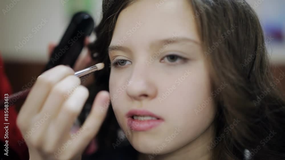 Makeup artist paint brush the eyes of the girl the teenager Makeup artist paint brush the eyes of the girl the teenager