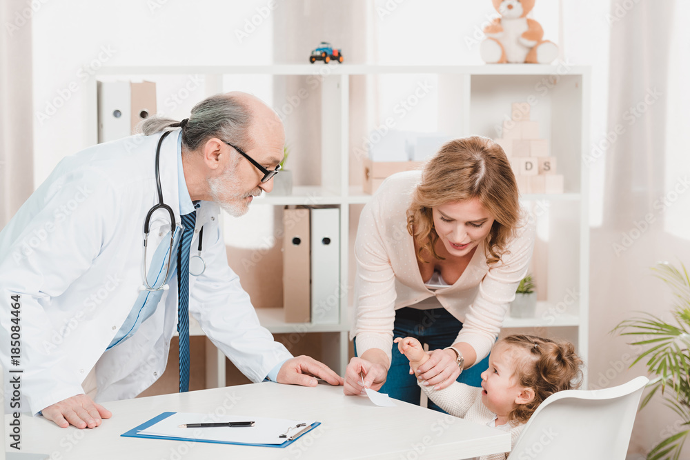 Fototapeta premium mother and crying little daughter at doctors reception in clinic