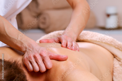 Massage therapist massaging shoulders and back of a male