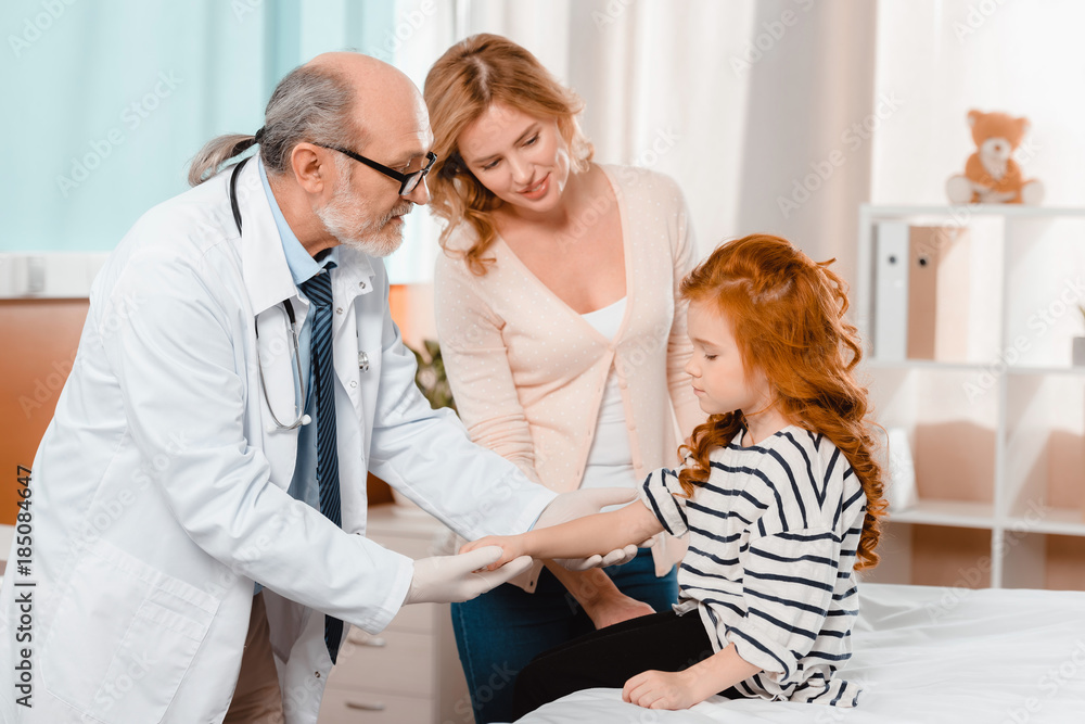 portrait of doctor in white coat and medical gloves examining cute little girl during reception in clinic portrait of doctor in white coat and medical gloves examining cute little girl during reception in clinic