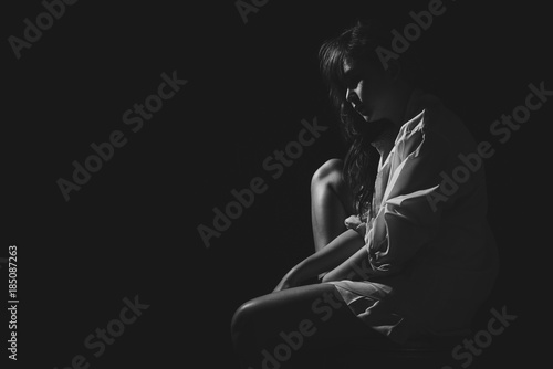 The depression woman sit on the chair on dark background, sad asian woman silhouette in dark, monochrome image. Free from copy space.