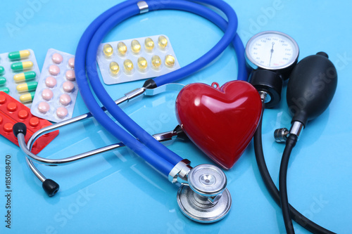 Stethoscope, red heart, asorted pils and medical equipmenton on blue background photo