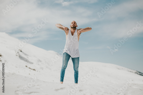 .Handsome young man dancing in the snow with bare feet. Taking joyful feelings, happy free and with dance. Lifestyle. © lubero