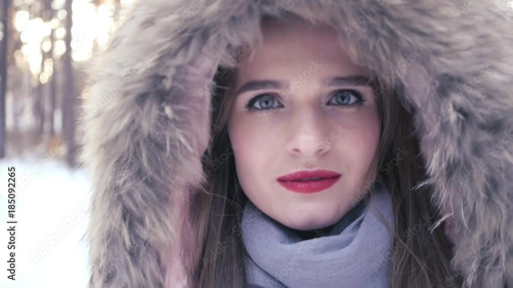A beautiful girl with a red lipstick in a hood with fur stands in a forest in the winter and turns away from the camera. HD, 1920x1080, slow motion A beautiful girl with a red lipstick in a hood with fur stands in a forest in the winter and turns away from the camera. HD, 1920x1080, slow motion