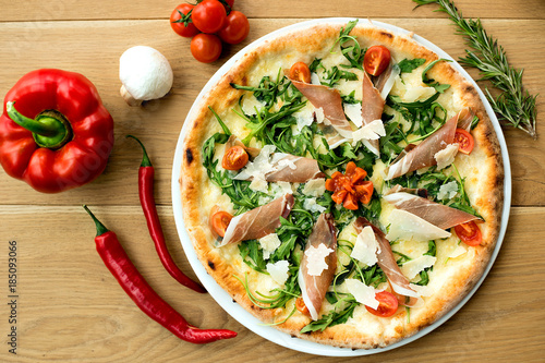 Delicious fresh pizza served on wooden table with vegetables