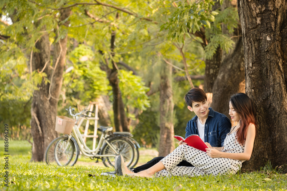 Asian couple lifestyle in park outdoor,reading book and listen to music for relaxation and happy in summer Asian couple lifestyle in park outdoor,reading book and listen to music for relaxation and happy in summer