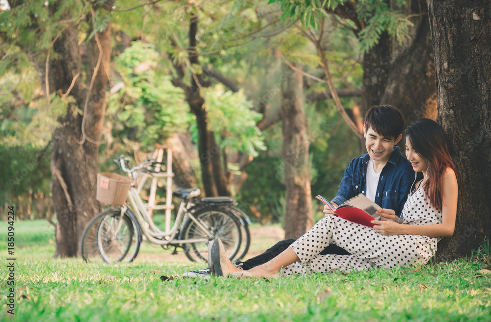 Asian couple lifestyle in park outdoor,reading book and listen to music for relaxation and happy in summer Asian couple lifestyle in park outdoor,reading book and listen to music for relaxation and happy in summer