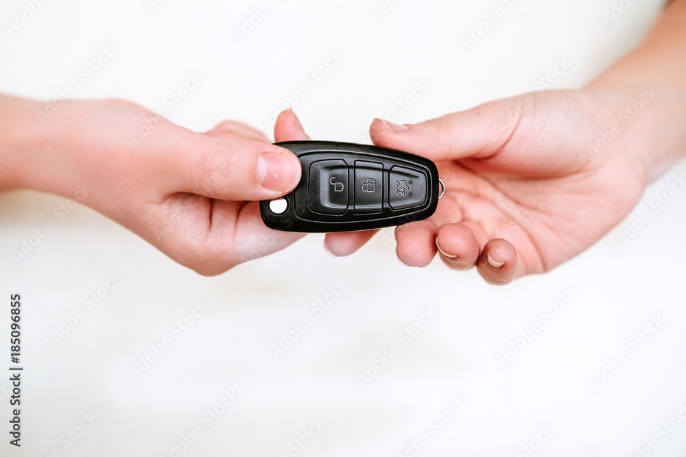 Fototapeta premium Young attractive girl passes the car keys to the buyer closeup