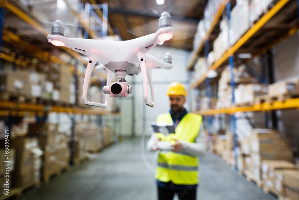 Man with drone in a warehouse. - obrazy, fototapety, plakaty 