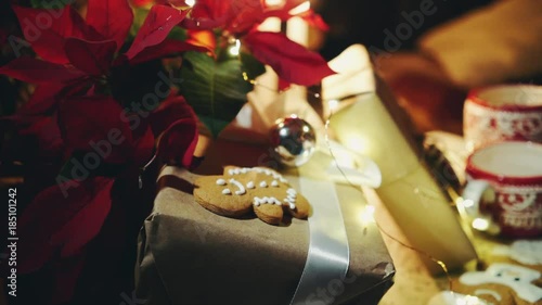 panoram at christmas still life poinsettia flower, gift boxes, candles and garland, burning fireplace at background, young female hand holding cup of hot tea photo