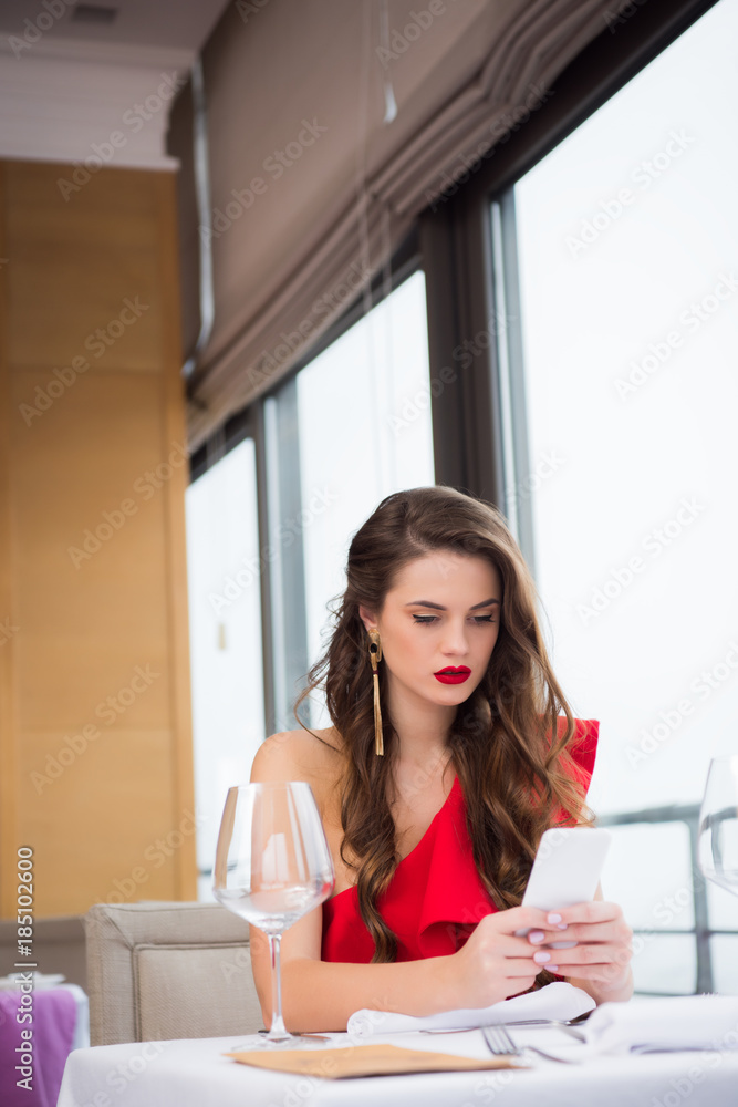 portrait of pensive beautiful woman using smartphone while waiting for boyfriend in restaurant portrait of pensive beautiful woman using smartphone while waiting for boyfriend in restaurant