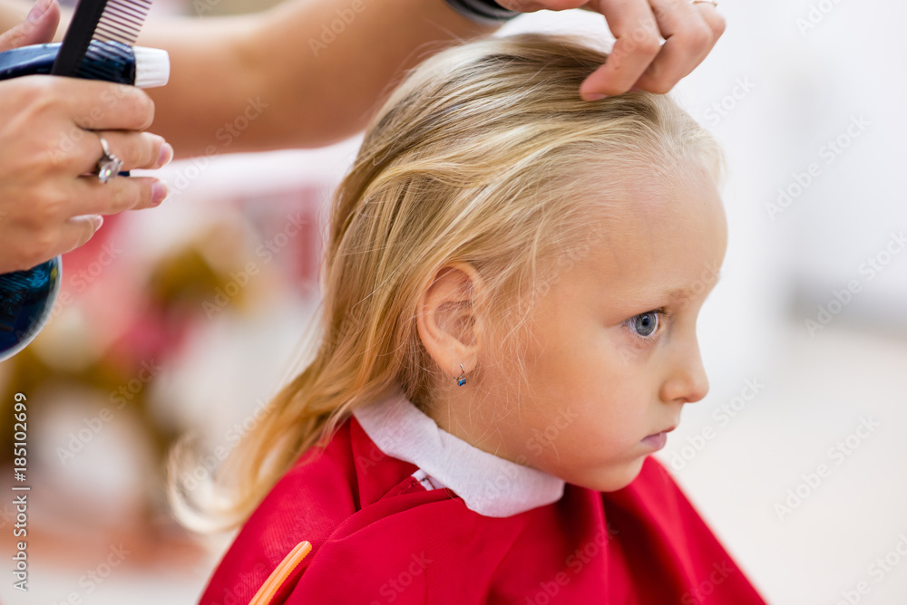 Fototapeta premium A little girl does a haircut.