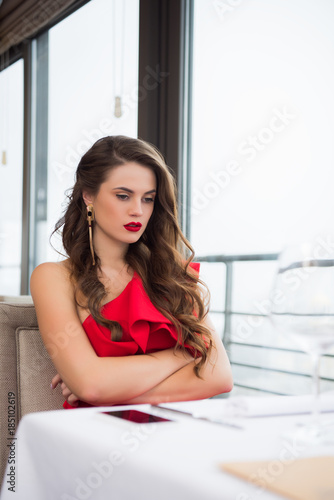 upset woman with arms crossed waiting for boyfriend on date in restaurant