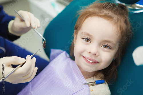 Child with cute smile sits at dentist chair with napkin
