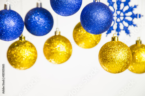 Closeup view of different Christmas ornaments isolated on white background. Colorful blue and golden shiny toys hanging on silver ropes. Horizontal color image.