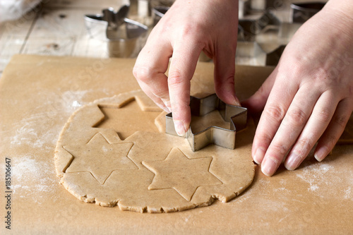 A woman rolls out the dough and cuts out the biscuits.