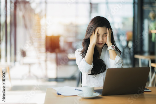 Overworked businesswoman suffering from headache and thinking how to end work.