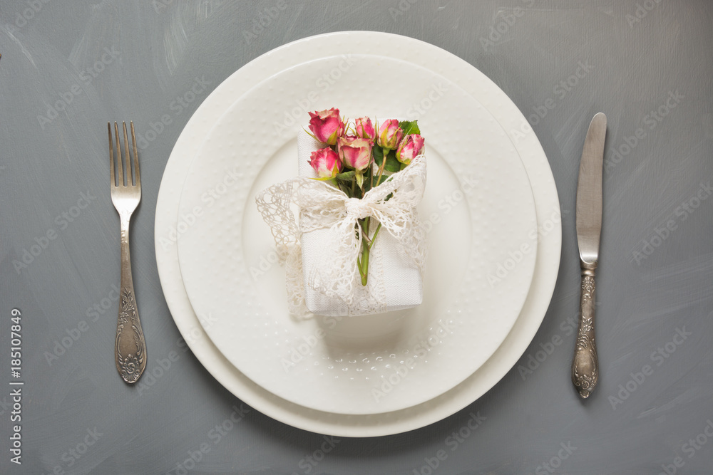 Festive table setting, female white gift with flowers, vintage dishware, silverware and decorations on gray. Top view. Concept. Festive table setting, female white gift with flowers, vintage dishware, silverware and decorations on gray. Top view. Concept.