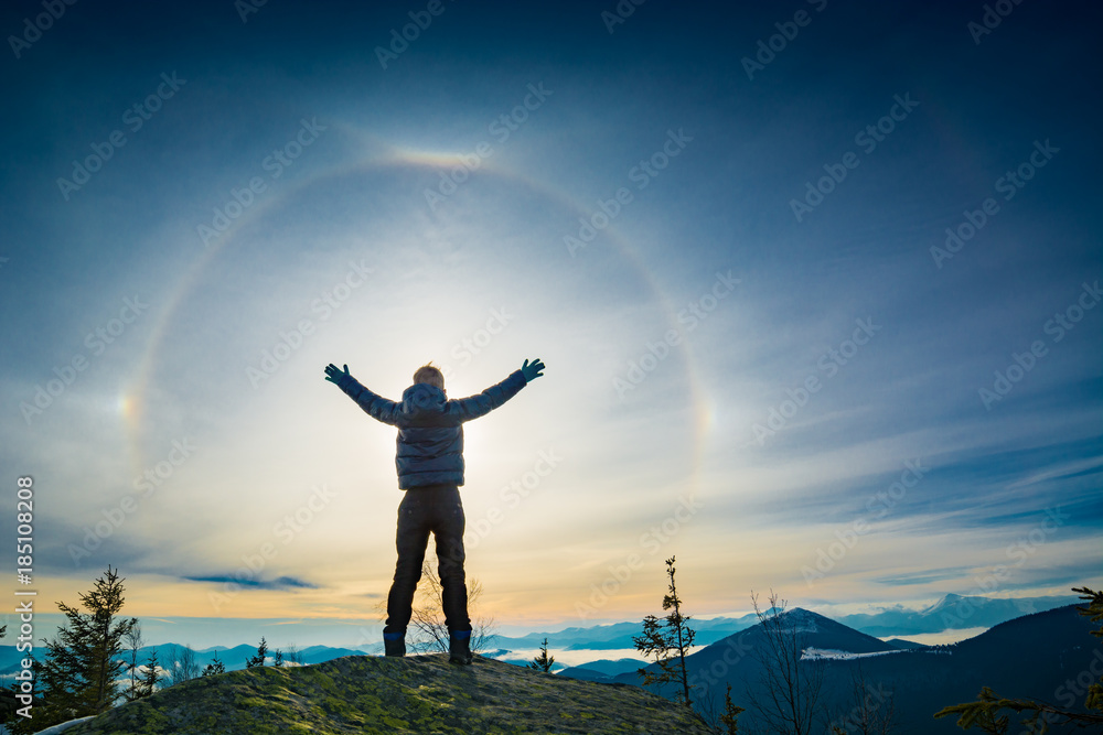 The boy hiker standing with raised hands on a top of mountain The boy hiker standing with raised hands on a top of mountain
