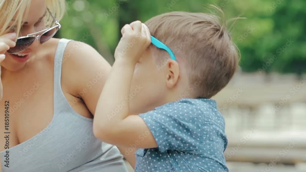 Young happy smiling mother in sunglasses with her son in the park Young happy smiling mother in sunglasses with her son in the park