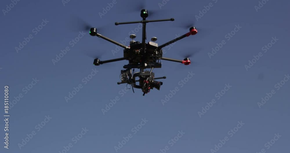 Large octocopter drone flying against blue sky Large octocopter drone flying against blue sky