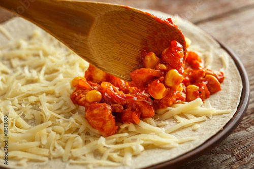 putting the filling on a flat cake with cheese. Preparation of the quesadilla, tacos, burito.