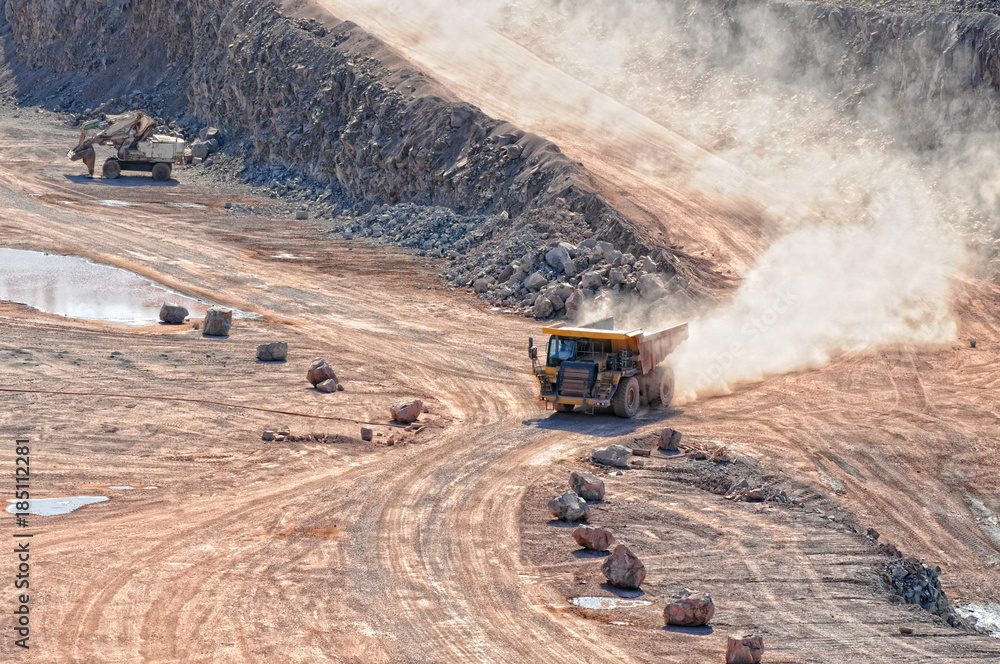 dumper truck driving in an active quarry mine of porphyry rocks. digging. dumper truck driving in an active quarry mine of porphyry rocks. digging.