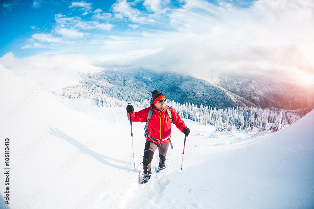 A man in snowshoes in the mountains. A man in snowshoes in the mountains.