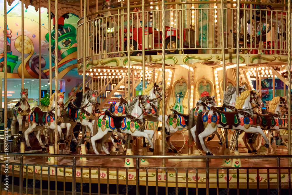 Circular children's carousel with colorful horses and cars