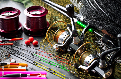 Fishing rods and spinnings in the composition with accessories for fishing on the old background on the table