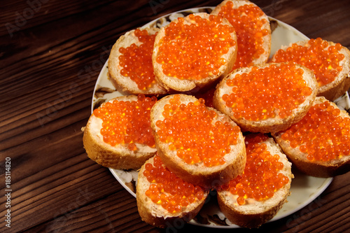 Sandwiches with butter and red caviar on wooden table