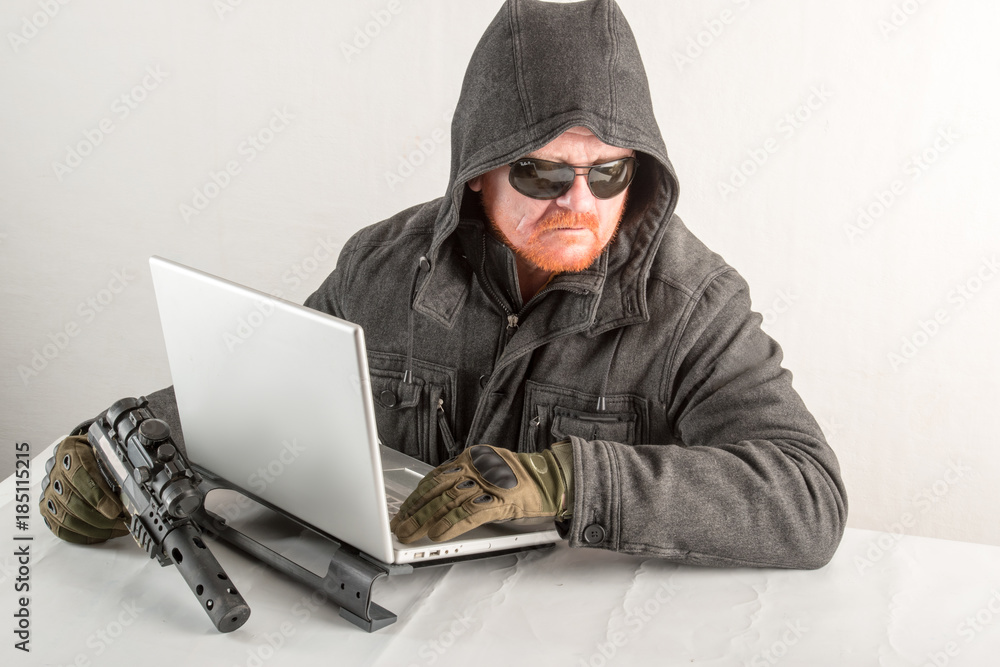 An evil hacker with a gun, red hair, a beard and a mustache. Penetration into the home, hacking laptop, emotion, cinema, sun glasses An evil hacker with a gun, red hair, a beard and a mustache. Penetration into the home, hacking laptop, emotion, cinema, sun glasses