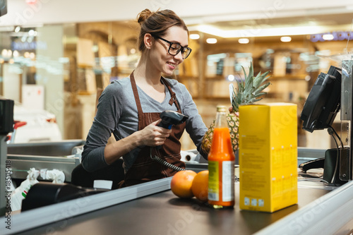 Smiling female cashier scanning grocery items photo