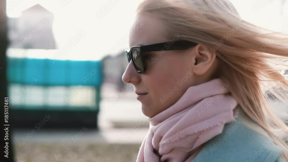 Portrait of confident Caucasian blonde girl 20s. Slow motion calm smiling young lady walking in stylish sunglasses. Portrait of confident Caucasian blonde girl 20s. Slow motion calm smiling young lady walking in stylish sunglasses.