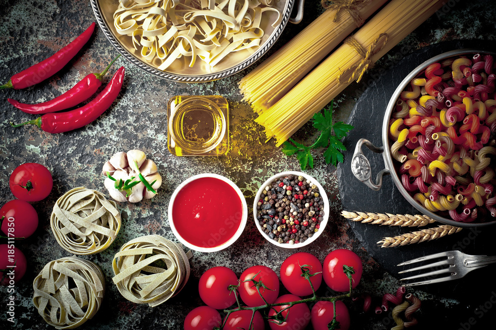 Raw pasta in the composition on the table with items for cooking Raw pasta in the composition on the table with items for cooking