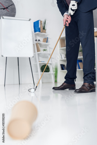 cropped shot of businessman playing golf in office