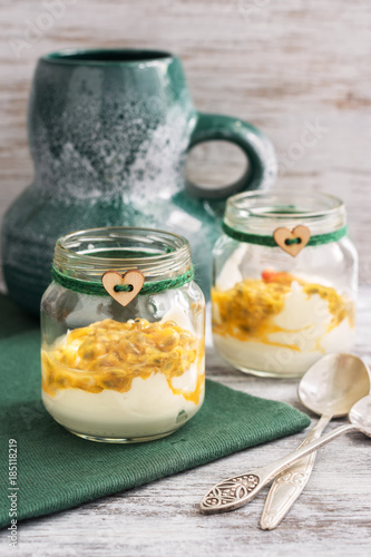 Yoghurt with passion fruit in a glass jar. A jar with a thread and a heart. Selective focus