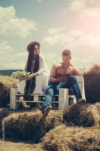 Couple in love sit on bench on hay