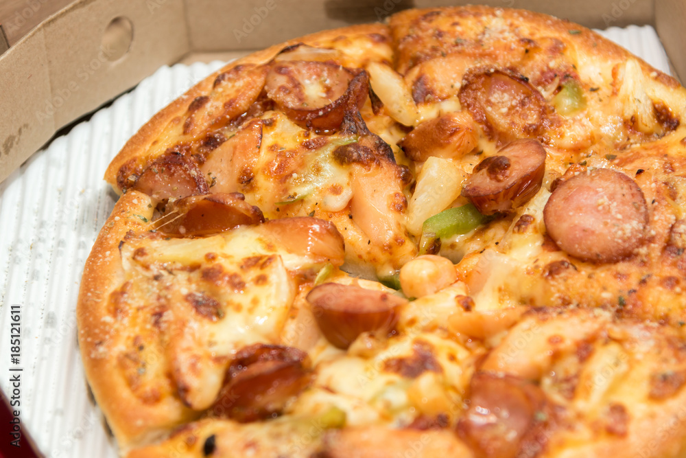 Close up of pizzas with variety of toppings and cheese in cardboard take out boxes with open lid Close up of pizzas with variety of toppings and cheese in cardboard take out boxes with open lid