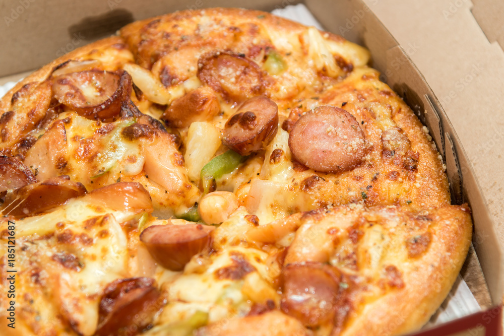 Close up of pizzas with variety of toppings and cheese in cardboard take out boxes with open lid Close up of pizzas with variety of toppings and cheese in cardboard take out boxes with open lid