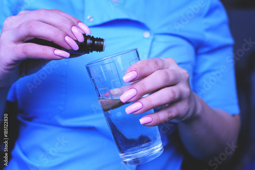 A young girl, the nurse puts drops in a glass of water. The treatment of poisoning.