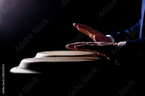 Hands of a musician playing on bongs in dark tones photo