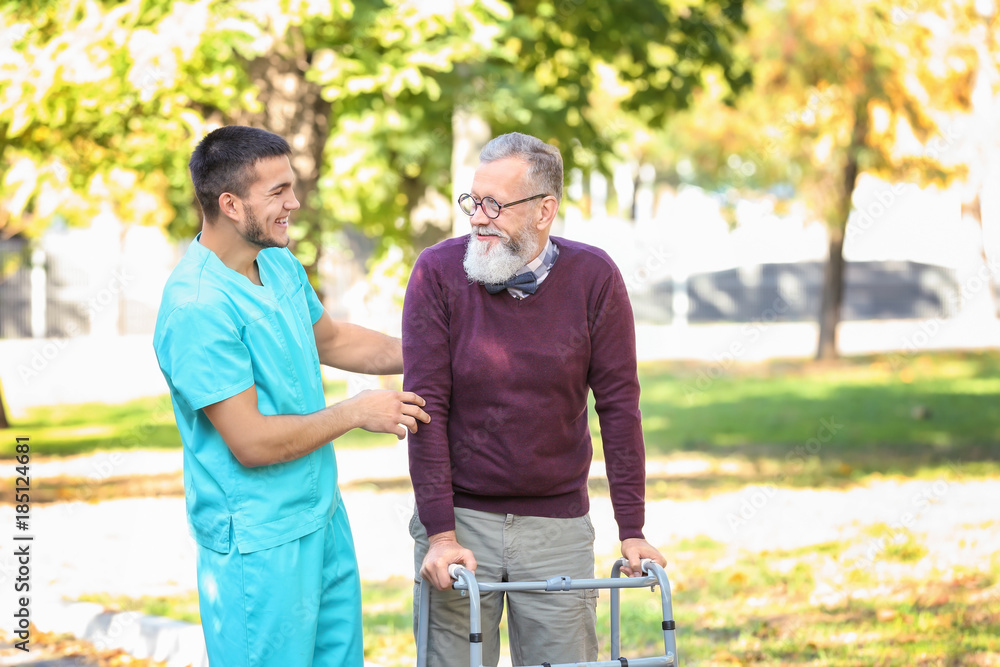 Young caregiver walking with senior man in park Young caregiver walking with senior man in park