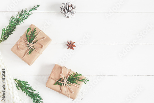 Christmas composition. Christmas gifts, fir tree branches, knitted blanket on white wooden background. Flat lay, top view, copy space