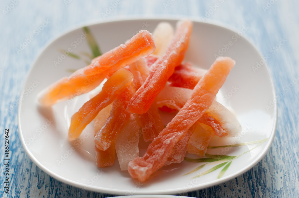 Candied papaya in a white plate on a wooden background Candied papaya in a white plate on a wooden background