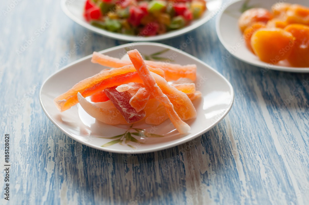 Candied papaya in a white dish on a wooden table Candied papaya in a white dish on a wooden table