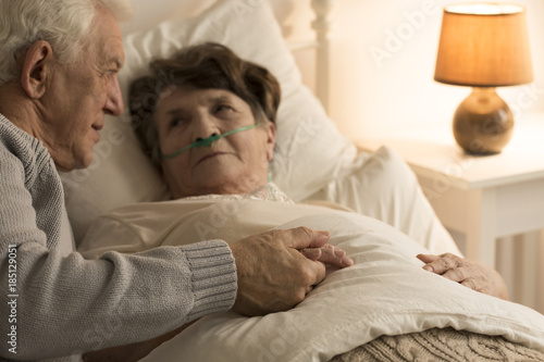 Elderly man supporting sick wife photo