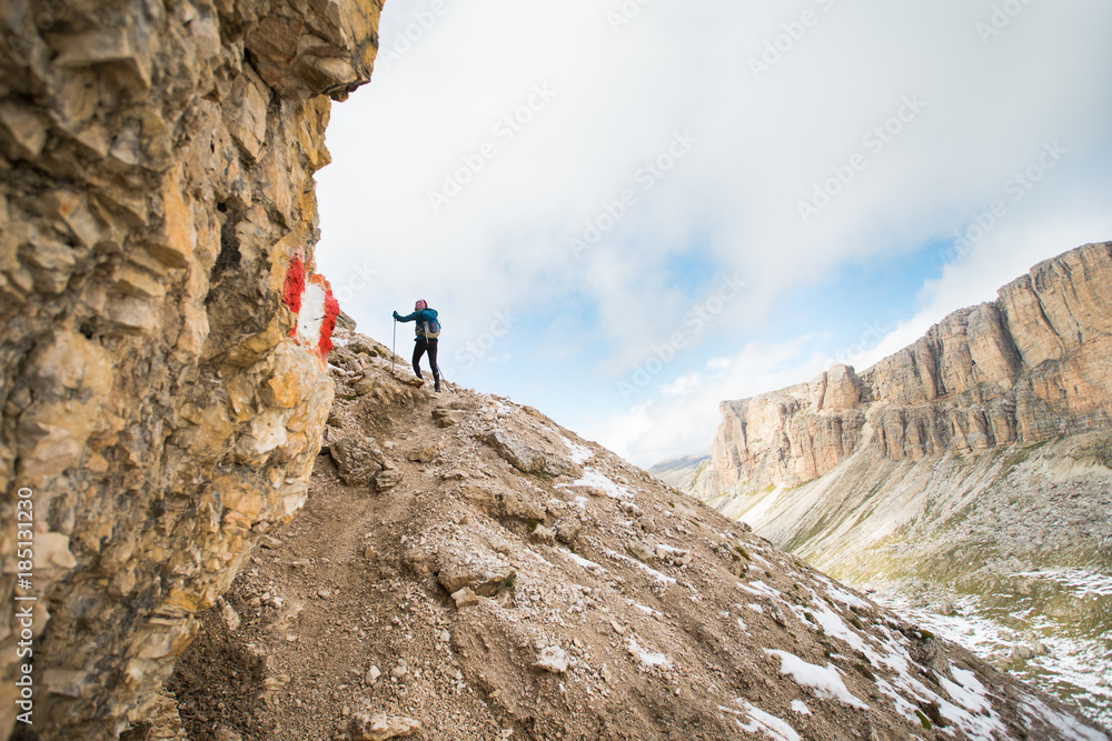 A single hiker climbing up a steep rocky trail in the Italian Dolomites 
